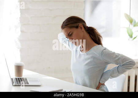 Affaticato giovani razza mista donna che soffre di sensazioni dolorose nel retro. Foto Stock