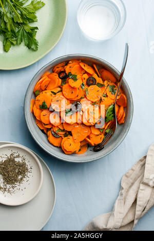 Marocchino tradizionale cotto Insalata di carote nord africana piatto vegano con il prezzemolo tritato e le olive su lastra grigia top view flat lay.sano cibo organico Foto Stock