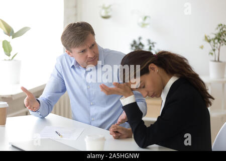 Mad team leader incolpando incompetente intern o partecipante. Foto Stock