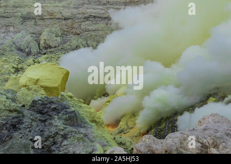 Fumo spesso sorge dalle bocche vulcaniche dentro il cratere del monte Vulcano Ijen, Java Orientale, Indonesia. Giallo zolfo nelle vicinanze. Foto Stock