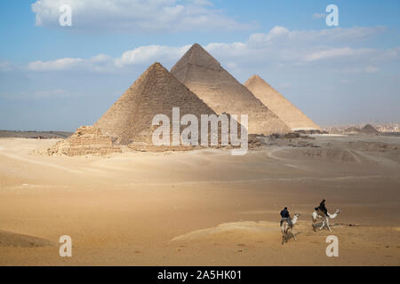 Egitto Giza, le grandi piramidi a Giza con gli uomini sui cammelli. Foto Stock