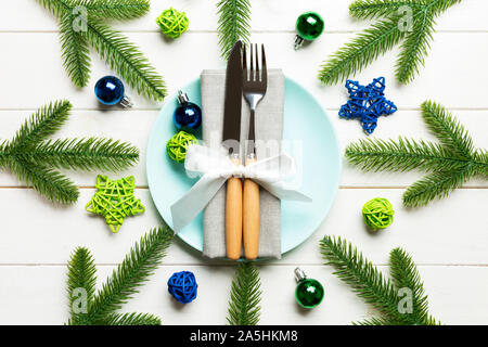 Vista superiore del nuovo anno la cena festiva su sfondo di legno. Composizione della piastra forcella, coltello, abete e decorazioni. Buon Natale concetto. Foto Stock