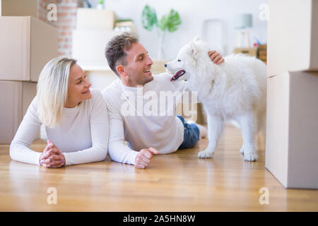 Giovane bella giovane con cane sdraiato sul pavimento a nuova casa intorno a scatole di cartone Foto Stock