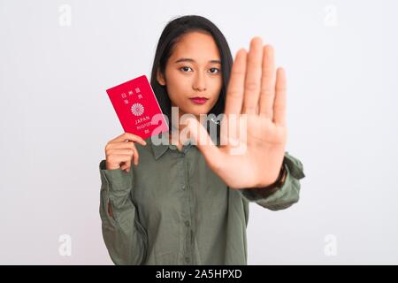 Bella donna cinese azienda giappone giapponese passaporto isolato su sfondo bianco con mano aperta facendo segno di stop con gravi e fiducioso expre Foto Stock