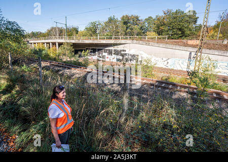 14 ottobre 2019, Assia, Frankfurt/Main: Katja Unterköfler (51) da quello ambientale amministrazione ferroviaria ha un piano di costruzione della vecchia S-Bahn linea vicino all'aeroporto di Francoforte. La linea sarà presto chiuso e ripristinato al suo stato naturale. Le strutture in calcestruzzo e ponti (in background) lungo il percorso sarà anche smantellato. In futuro, i treni roll over nuovi brani al Gateway Gardens S-Bahn fermata all'aeroporto. Foto: Frank Rumpenhorst/dpa Foto Stock