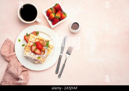 Cialde belghe con fragole e tazza di caffè sul fondo rosa, table top view con copia spazio. Dolce gustoso cibo a colazione Foto Stock