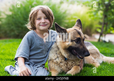 5 anno vecchio ragazzo giocando con il suo Pastore Tedesco cane sul prato verde Foto Stock