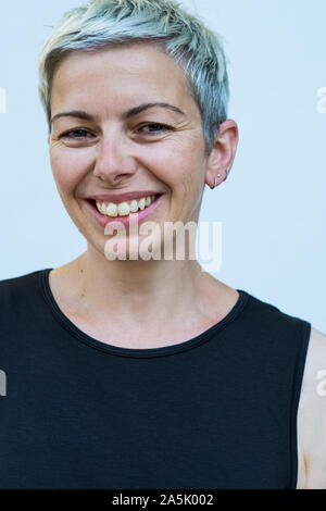 Donna con breve capelli grigi indossare top nero sorridente alla fotocamera. Foto Stock