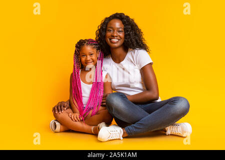Bella mom nero seduto sul pavimento con la sua figlia carino Foto Stock