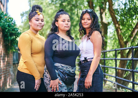 Giovane donna in posa con sorelle adolescenti da park, ritratto Foto Stock