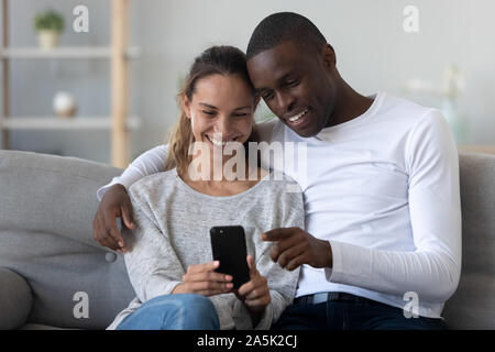 Felice coppia internazionale potrete rilassarvi sul lettino usando il cellulare insieme Foto Stock