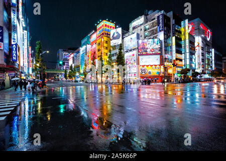 Luci al neon e cartelloni pubblicitari su edifici di Akihabara a notte piovosa, Tokyo, Giappone Foto Stock