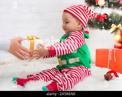 Adorable baby boy in costume di ELF ottenendo un regalo di Natale Foto Stock