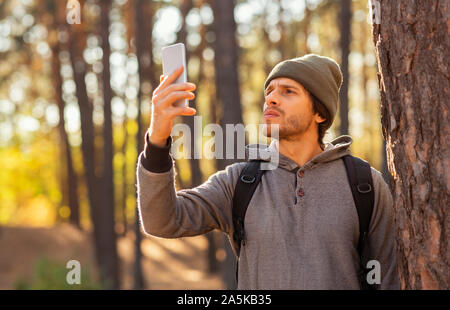 Guy controllo per internet mobile nel mezzo della foresta Foto Stock