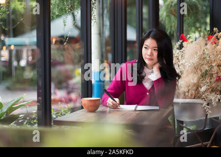 La donna nella scrittura di appunti in cafe Foto Stock