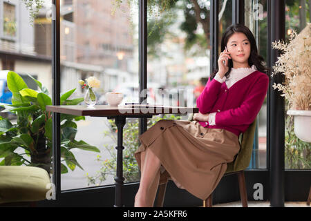 Donna che parla al telefono in cafe Foto Stock