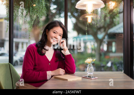 Donna sorridente in seduta cafe Foto Stock