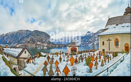 HALLSTATT, Austria - 25 febbraio 2019: panorama innevato del cimitero di Maria am Berg Chiesa Parrocchiale con filari di croci di legno, guarnita con tetti; Foto Stock