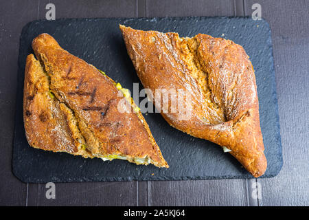 Pane rustico con avocado formaggio e miele, sulla superficie nera Foto Stock
