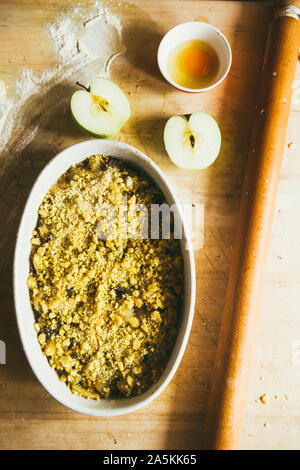 Serie di fotografia come fare un mele crumble , dagli ingredienti alla fine torta, ambiente rustico, pezzi di pasta frolla coprire le mele Foto Stock