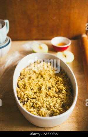 Serie di fotografia come fare un mele crumble , dagli ingredienti alla fine torta, ambiente rustico, pezzi di pasta frolla coprire le mele Foto Stock