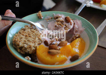 Semi-mangiare sano stile mediterraneo prima colazione compresa alcune berry yogurt, avena, mandorle e fette di pesche. Colorate, nutriente e gustosa! Foto Stock