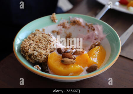 Semi-mangiare sano stile mediterraneo prima colazione compresa alcune berry yogurt, avena, mandorle e fette di pesche. Colorate, nutriente e gustosa! Foto Stock