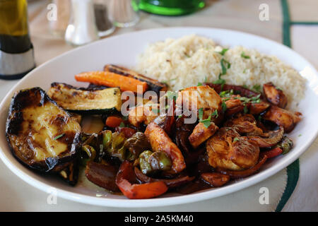 Cena in Cipro compresi alcuni carne piccante, riso bollito e verdure alla griglia come la carota e la zucchina. Un sano e delizioso stile mediterraneo piatto. Foto Stock