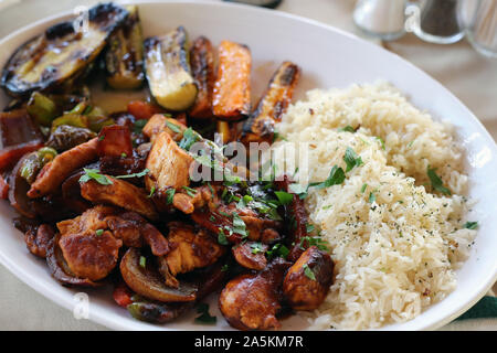 Cena in Cipro compresi alcuni carne piccante, riso bollito e verdure alla griglia come la carota e la zucchina. Un sano e delizioso stile mediterraneo piatto. Foto Stock