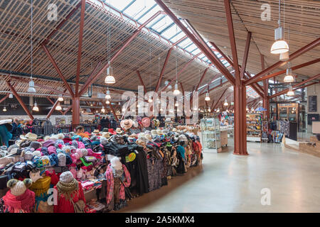 Banchi di abiti colorati all'interno dell'ampia architettura moderna in legno e acciaio del mercato Balti Jaama Turg a Tallinn, in Estonia Foto Stock