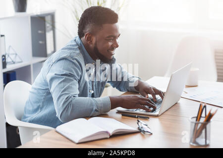 Ritratto di sorridere un dipendente che lavora sul computer portatile in ufficio Foto Stock