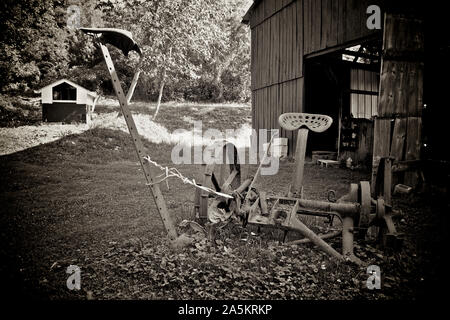 Vecchio arrugginito falce fieno al di fuori di un fienile. Foto Stock