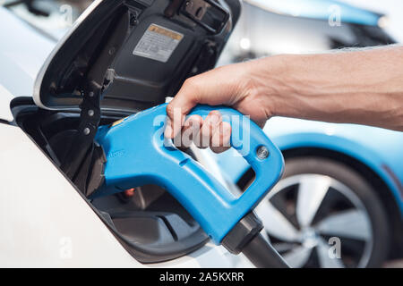 Giovane uomo adulto tenendo la potenza di alimentazione del cavo di ricarica per auto elettriche Foto Stock