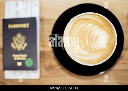 Foto in alto di un latte con un passaporto sfocato il tavolo Foto Stock