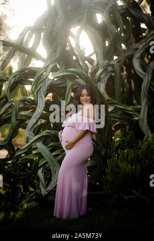 Gravidanza mom per essere in posa accanto ai grandi piante succulente Foto Stock