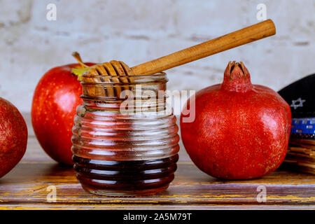 Versando il miele su apple e melograno con simboli di miele ebraica di Nuovo Anno Rosh Hashanah. Foto Stock