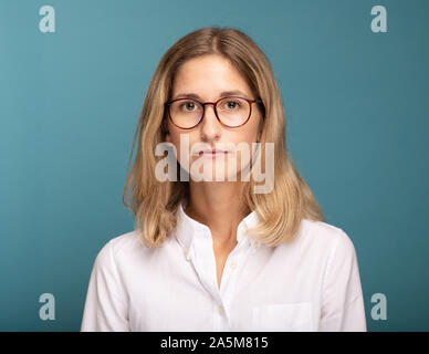 Ritratto di una bionda imprenditrice con gli occhiali di fronte a sfondo blu Foto Stock