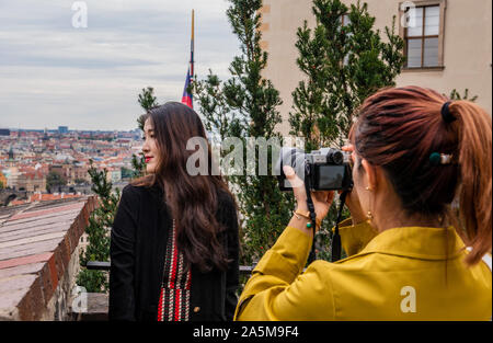 Donna prendendo vista laterale fotografia di amico, cityscape in background, Praga, Repubblica Ceca Foto Stock