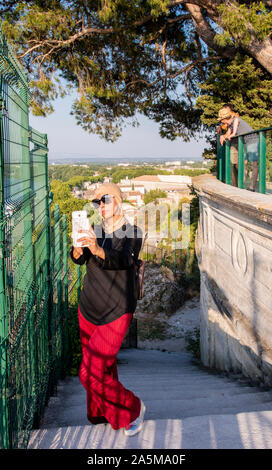 Musulmani turistica prendendo selfie, vista panoramica sullo sfondo, Avignon la cattedrale di Notre Dame e quadrato, Avignone, Provenza, Francia Foto Stock