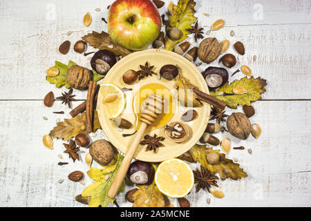 Composizione di autunno con noci, miele, semi, spezie, ghiande, castagne, frutti e foglie di autunno. Vista superiore, piatto laici. Foto Stock