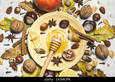 Composizione di autunno con noci, miele, semi, spezie, ghiande, castagne, frutti e foglie di autunno. Vista superiore, piatto laici. Foto Stock
