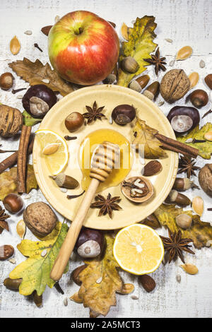 Composizione di autunno con noci, miele, semi, spezie, ghiande, castagne, frutti e foglie di autunno. Vista superiore, piatto laici. Foto Stock