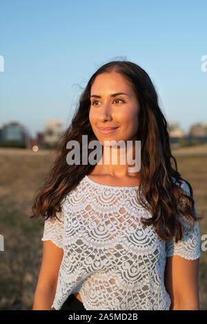 Ritratto di una giovane donna guardando il tramonto sull'oceano Foto Stock