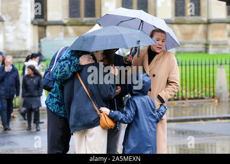 I turisti sono visti si ripara dalla pioggia sotto gli ombrelloni in un giorno di pioggia a Londra. Foto Stock