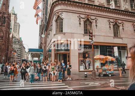 New York, Stati Uniti d'America - 17 Giugno 2017: persone di passaggio sulla strada principale crocevia di New York con la costruzione di bandiere e di sfondo. Angolo di Massimo Dutti shop. Foto Stock