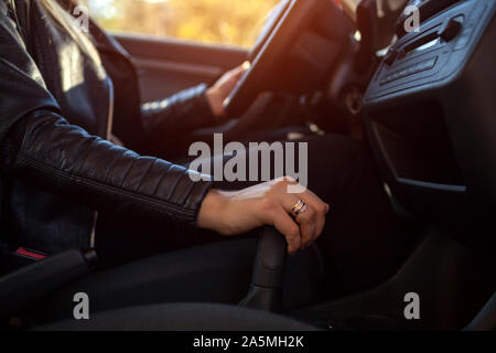 Donna alla guida. Autista tenendo la mano sulla trasmissione e sterzo. Proprietario iniziando la sua auto. Close-up Foto Stock