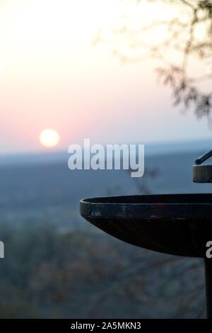 Carbone di legna per barbecue braai camino incorniciato da una bussola veld sunrise nel Parco Nazionale di Kruger in Sud Africa Foto Stock