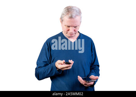Un anziano uomo sceglie tra un vecchio telefono e uno smartphone. Isolato su uno sfondo bianco. Foto Stock
