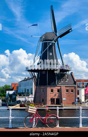 Bicicletta sul ponte con il mulino a vento De Adriaan sullo sfondo, Haarlem; Paesi Bassi Foto Stock