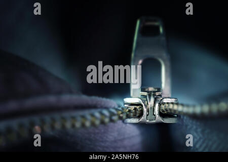 Cerniera lampo in metallo macro shot, incisivo invenzione tecnica di cucito e di industrie di abbigliamento, blu scuro-uno sfondo grigio con spazio di copia selezionato, focus, n Foto Stock